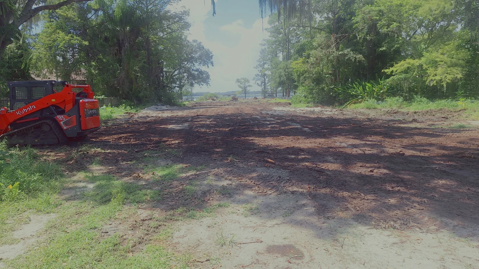 Kubota SVL75-3 compact track loader grading a cleared lot in Dover, FL — land clearing and dirt work by Branching Out Tree Services